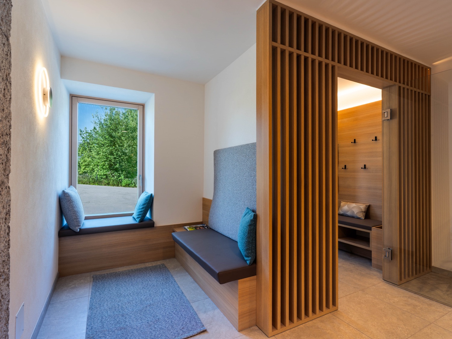 Heller Wartebereich einer Praxis mit Fensterbank-Sitz und Holz-Lamellenwand